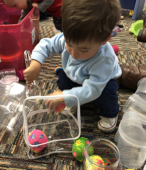 toddler playing with contents in a bag
