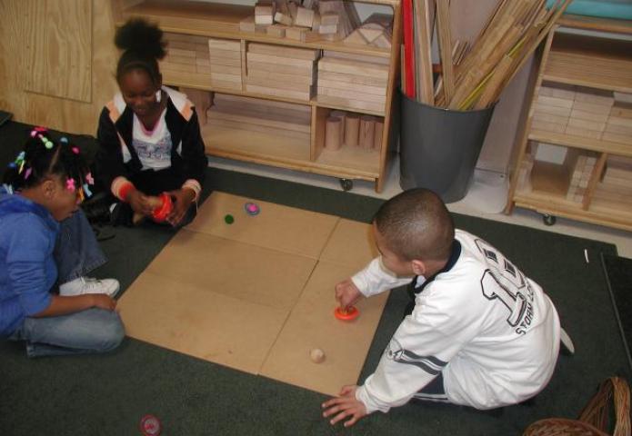 Children playing with spinnin toys on the floor.