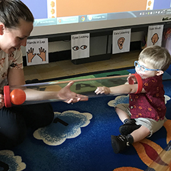 Teacher sitting on the floor with a small child.