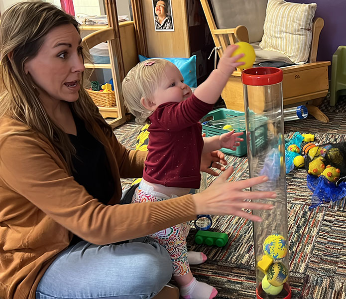 Infant putting a ball into a tube