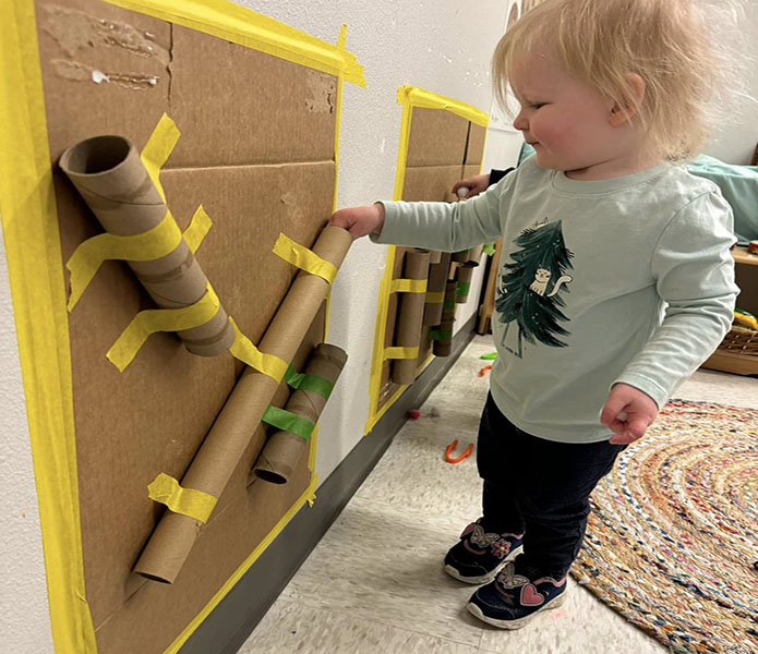 toddler putting a ball through a cardboard tube