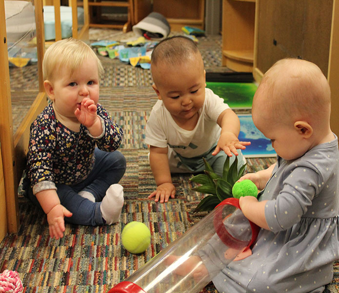 infants playing with a tube and balls