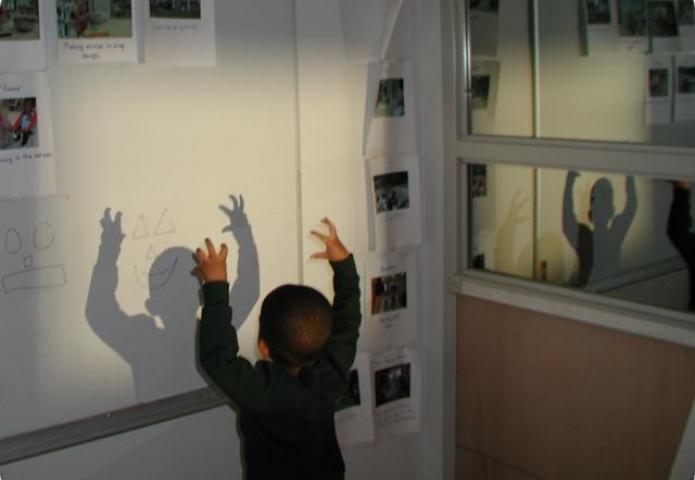 Child creating shadows on classroom wall.