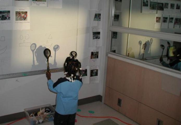 Child with two utensils creating shadows.