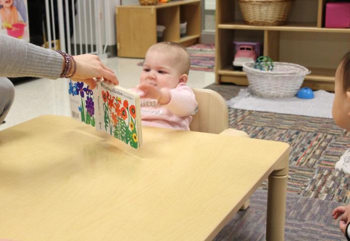 Child reaching for a picture book.