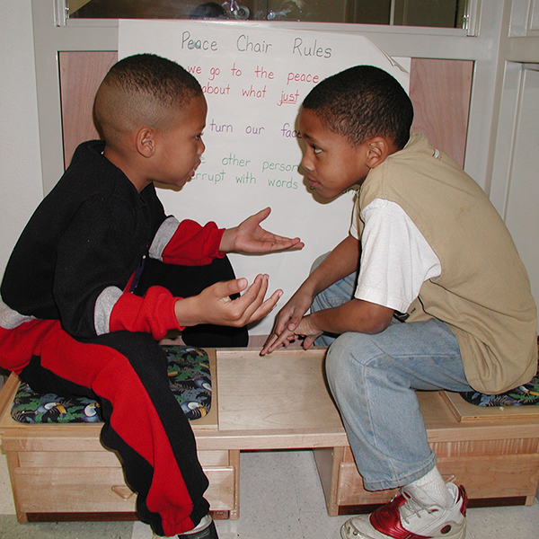 Two boys talking in front of a poster.