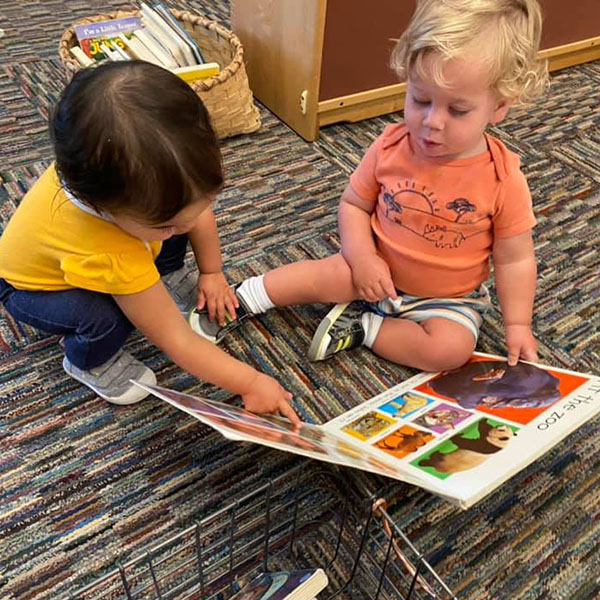 Two toddlers looking at a picture book.