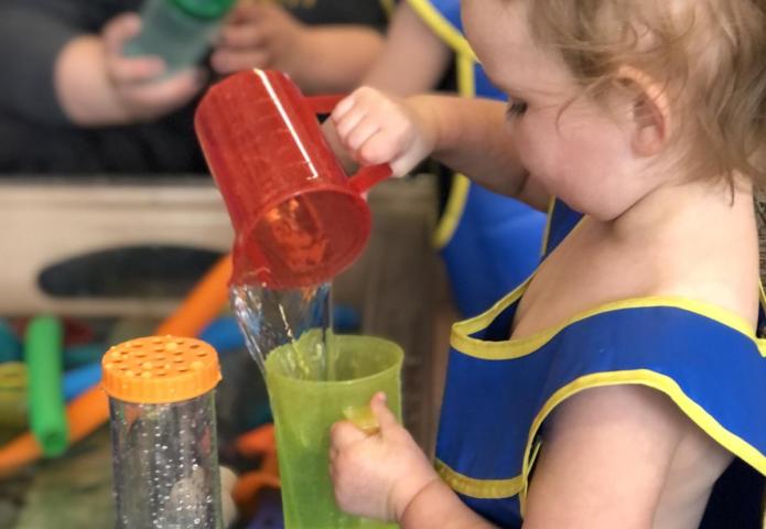 Blue dress girl pouring a cup of water.