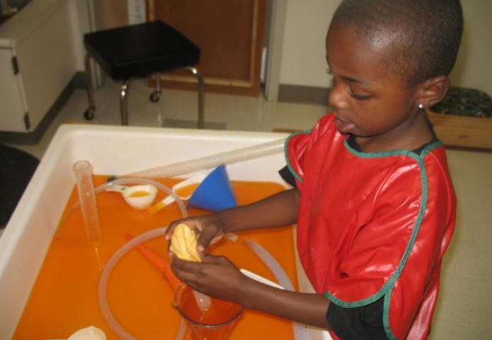 Child filling cup with orange juice.