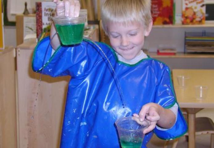 Child transfering liquid to a cup.