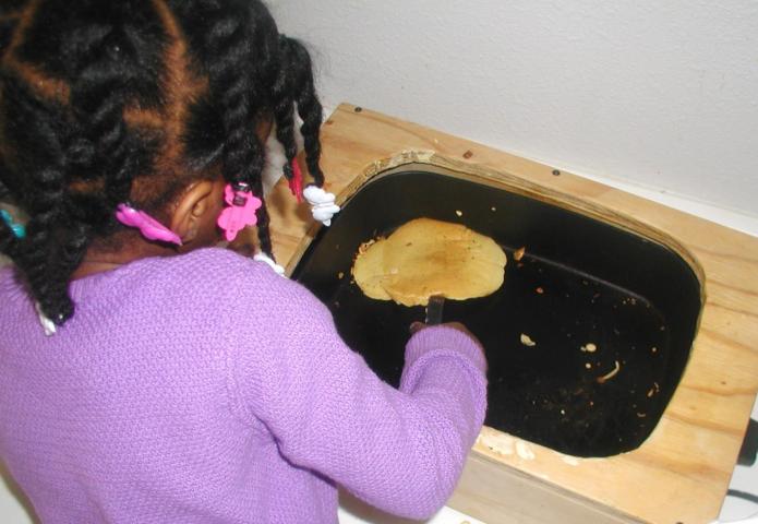 Young girl flipping a pancake.