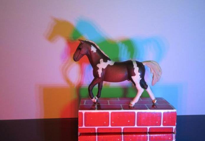 A horse toy reflecting shadows on the wall.