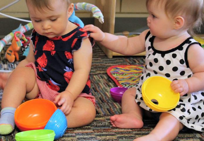 Two babies playing with plastic toys.