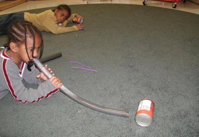 Student playing with a tube and a can.