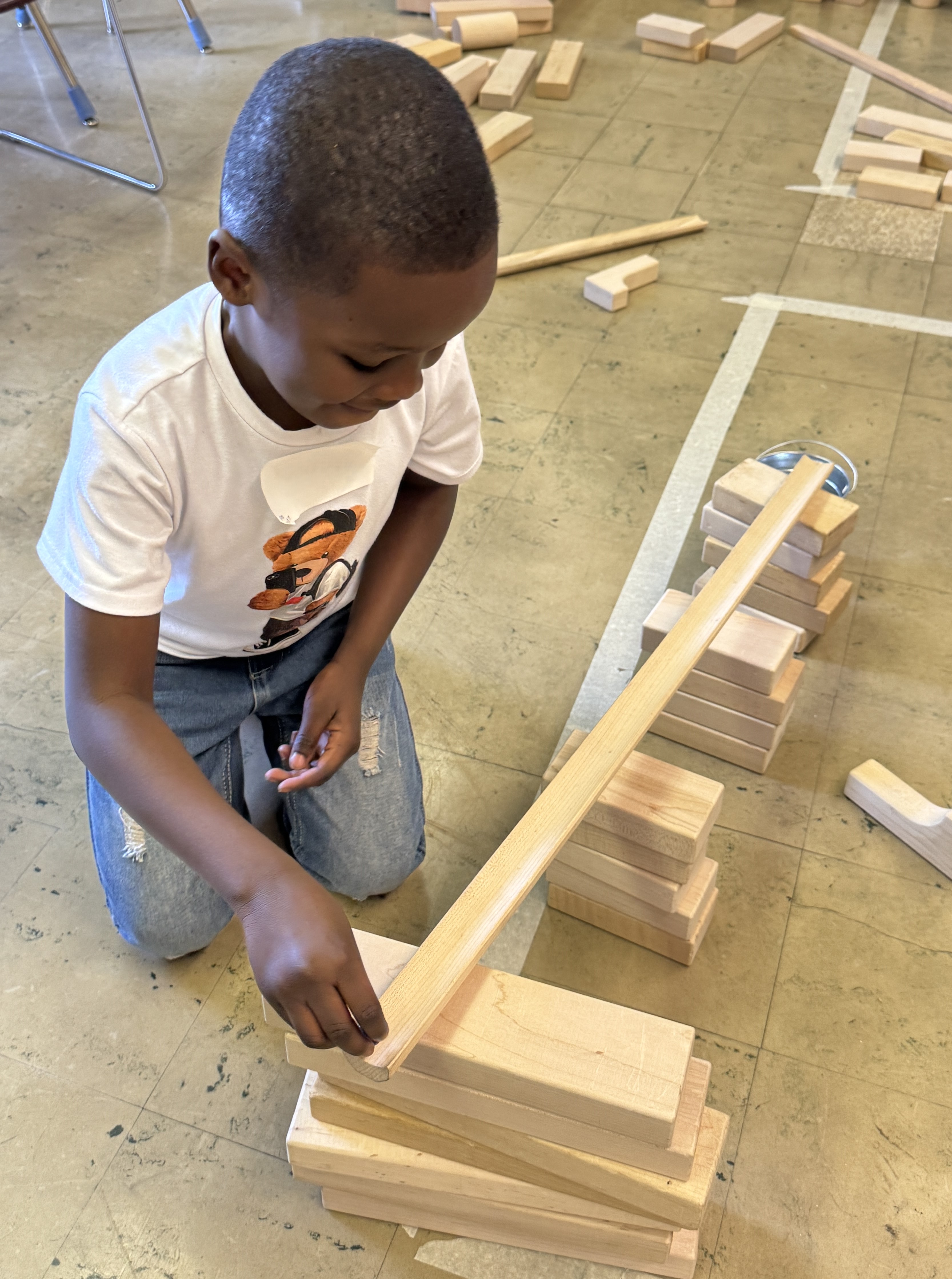 Young boy putting a marble on a wooden ramp