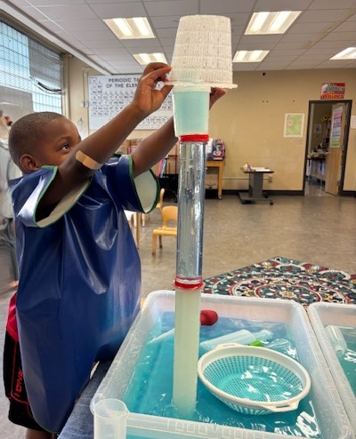 Young boy pouring water through a container and tubes