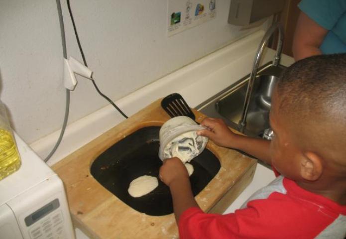 Child making pancakes in a skillet