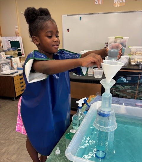 Young girl pouring water through a funnel