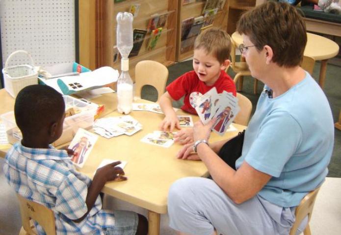 Teacher playing card game with two young children