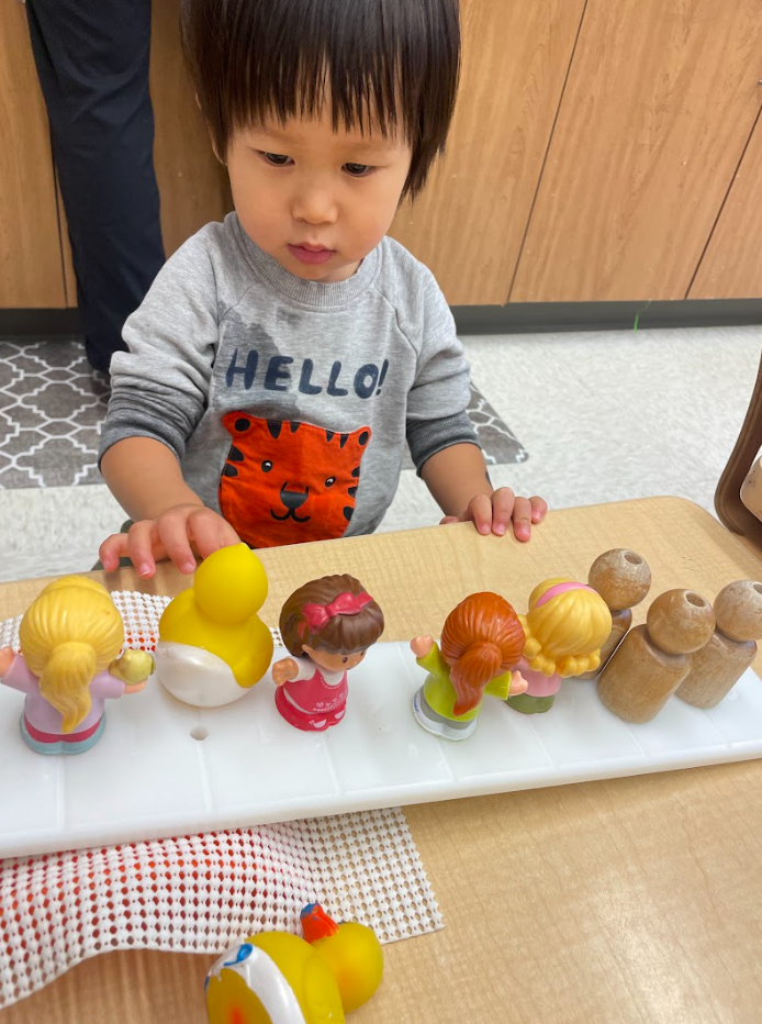 toddler balancing materials on balance scale