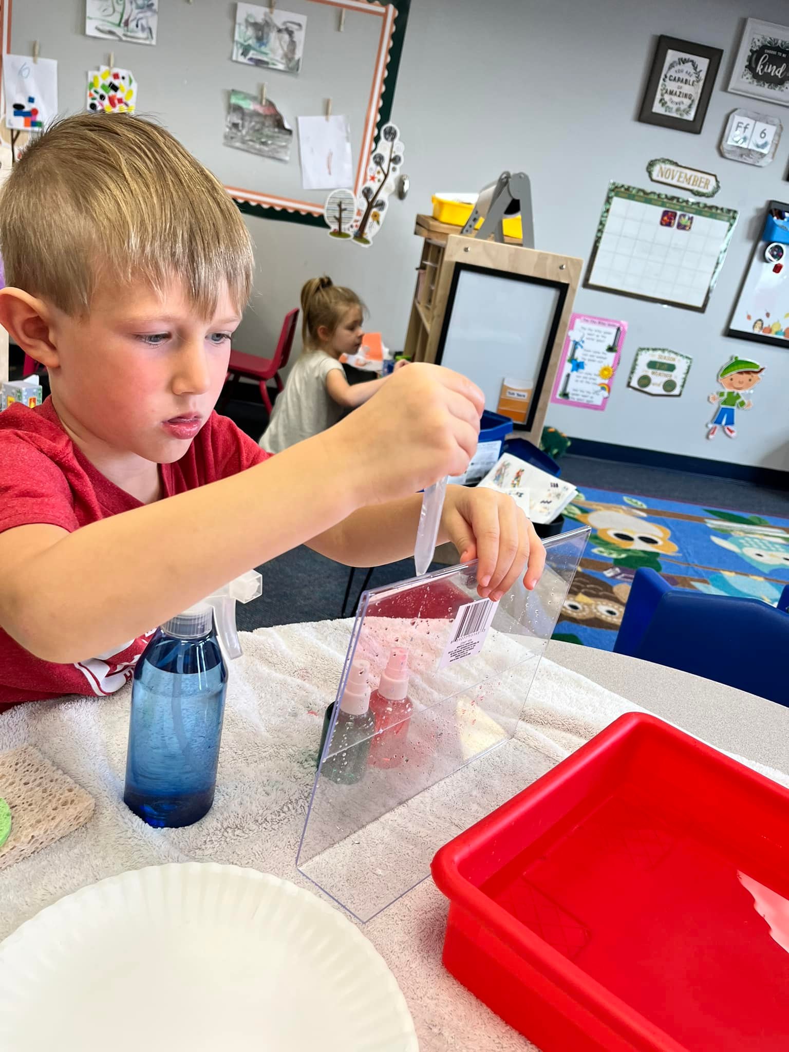 Young child squeeze water from an eye dropper onto a clear screen