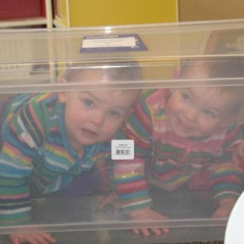 Two infants looking through a clear tub