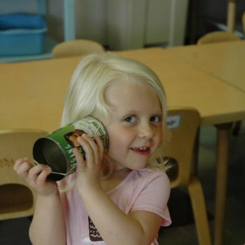 young girl listening to a tin can while plucking a rubber band