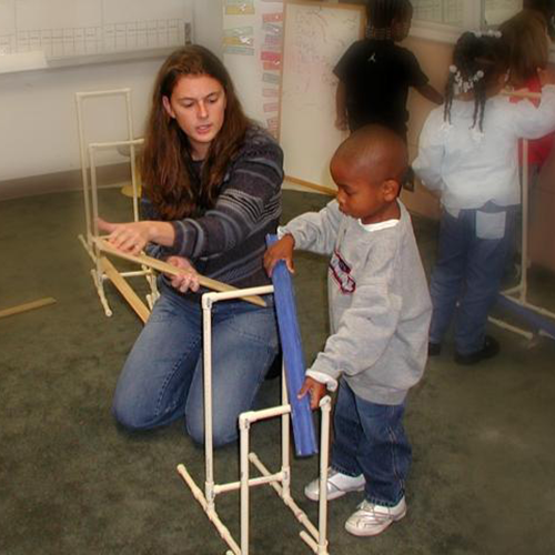 A boy and teacher building ramps and pathways