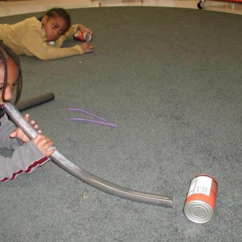 Child blowing a tin can through a tube